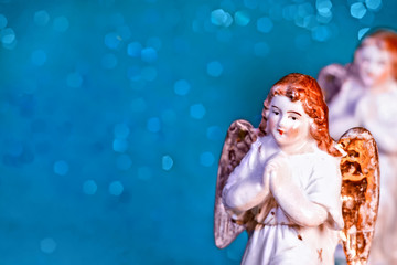 Porcelain angel on green bokeh background with copy space