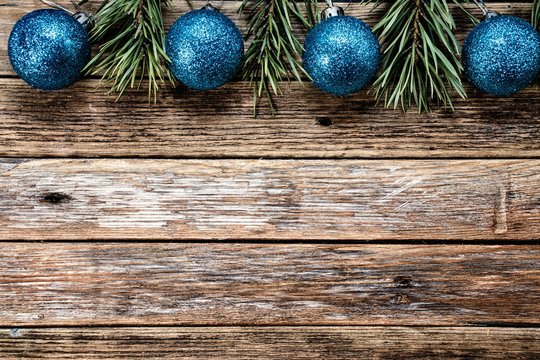 Christmas blue balls and pine branches on wooden background. Winter holiday concept. View from above. Copy space