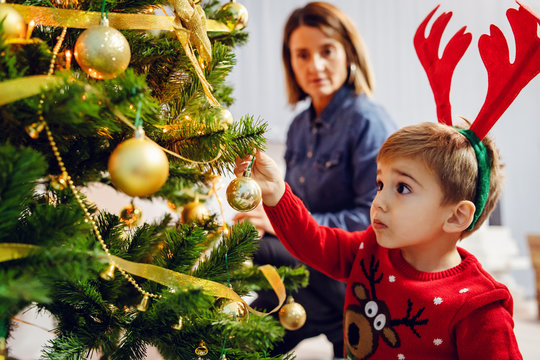 Woman And Her Son Or Grandson Mother Or Grandmother Sitting By The Christmas Tree Decorating At Home Family Single