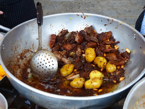 Big metal bowl of Fritada, fried pork meat with corn, tostado and potatoes, traditional homemade ecuadorian and Latin American food. 