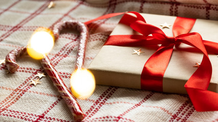 Rustic craft gift box with a red bow and candy canes. Christmas handmade present for Merry Christmas and New year holiday. New Year Christmas present wrapped ribbon. 