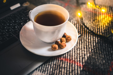 Christmas lights and a cup of warm tea with nuts, a cozy plaid, a winter atmosphere