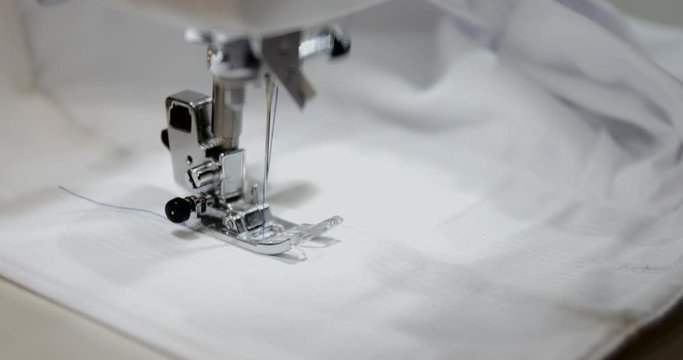 professional 4K shot of sewing maching making embroidery on Light grey fabric