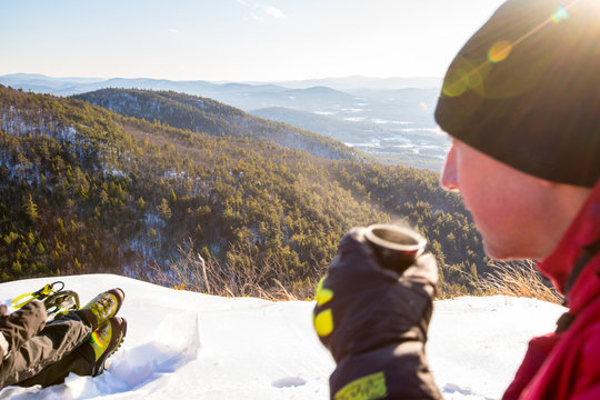 A man has a cup of hot tea on the summit of the popular Peaked Mountain in the Green Hills Preserve.