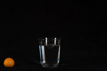 glass of water with orange on black background