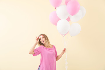 Beautiful young woman with balloons on color background