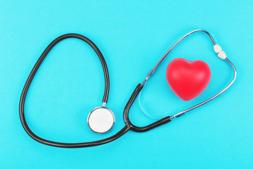 Red heart and stethoscope on a blue background. Health care concept, health worker, heart health care, medical care. Flat layout, top view.