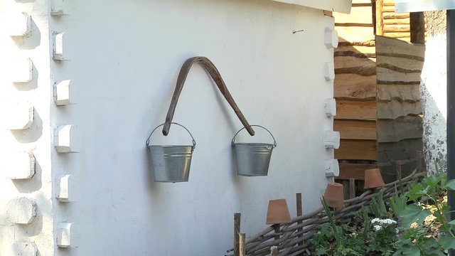 Zinc buckets with a yoke hanging on a wall in an ethnographic museum as household items of ancient peoples