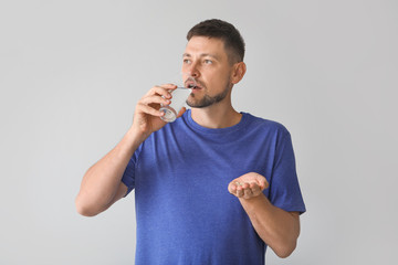 Man taking pills on light background