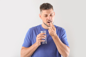 Man taking pill on light background