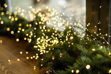Fototapeta na wymiar christmas lights with pine on the windowsill