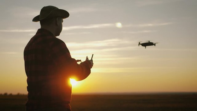 Silhouette of a farmer using a drone in a wheat field at sunset. Concept technology innovations for increasing productivity in agriculture.