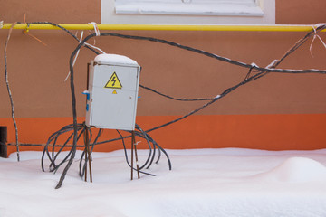 Electricity warning box, with cables around and wall background. Construction site