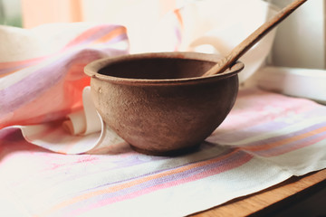 rustic flat lay, clay mortar with wooden pestle for grinding spices on linen background and string of onions on windowsill