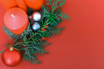 spruce branches with Christmas balls of different colors and  4 red Christmas candles on a red background in the corner place for text. concept new year and Christmas