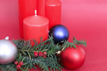 spruce branches with Christmas balls of different colors and  4 red Christmas candles on a red background in the corner place for text. concept new year and Christmas