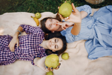 Fototapeta premium Beautiful girls in a summer park. Friends lying on a blanket. Ladies on a picnic