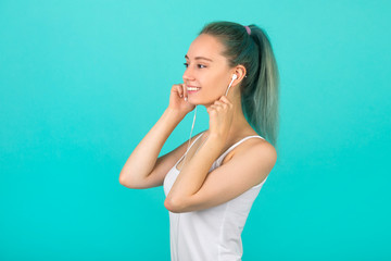 beautiful young slim woman in sportswear on a blue background listens to music