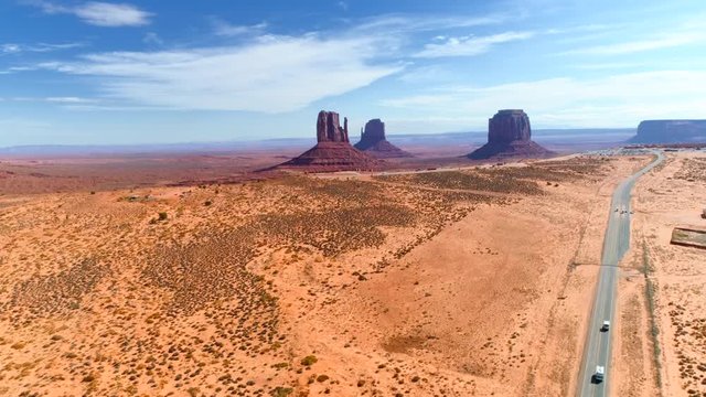 Outstanding aerial 4K view over the famous american Wild West landmark, the sandstone formations of Monument Valley. Three huge natural monuments on the background of wast Colorado Plateau.