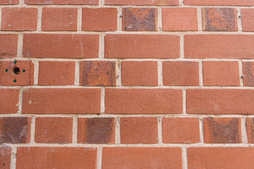 A background of red and brown bricks with white cement holding them together