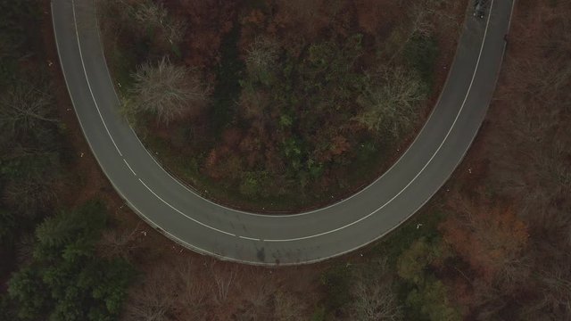 Blick von oben auf zwei gegensätzlich fahrende Autos in einer Kurve im Herbst