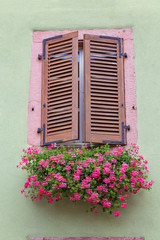 Fototapeta na wymiar Window with closed wooden shutters on ancient wall