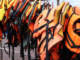 Fototapeta na wymiar Many orange life jackets hang in a row