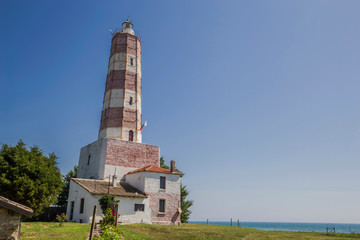 Obraz premium Lighthouse on sea shore in sun light