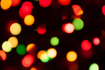 Obraz premium unfocused colorful christmas lights on dark background with bokeh effect and copy space