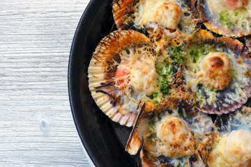 Baked scallops with cheese and spicy sauce. Delicate clam is a real pleasure. Romantic dinner at a Spanish fish restaurant. Mallorca Island, Spain.