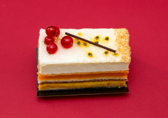 multilayer cake with airy white cream and red currant, mouth watering dessert, on a red background