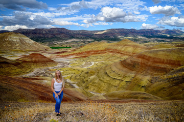 Attractive blond young woman is impressed by the view of the Painted Hills Unit - John Day Fossil Beds National Monument, Oregon, USA