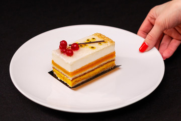 multi layered beautiful cake with white cream and red currants, on a white plate, dessert serving