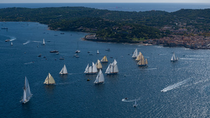 French Riviera - modern and old sail race above aerial view in St -Tropez gulf with Saint tropez village in background