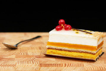 multilayer cake with air cream and red currants on a wooden background