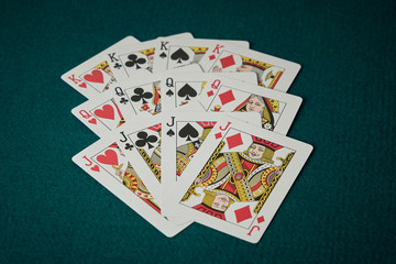 Cards of the four kings, queens and jacks on green poker game board mat.