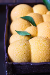 Orange or tangerine shape mousse pastry dessert covered with orange velour (velvet spray) on dark mirror background. Modern European cake. French cuisine.