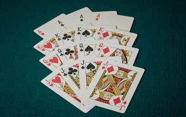 Cards of the four kings, queens and jacks on green poker game board mat.