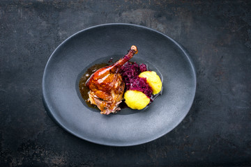 Traditional roasted Christmas duck leg with blue kraut and potato dumpling as top view on a modern design plate © HLPhoto