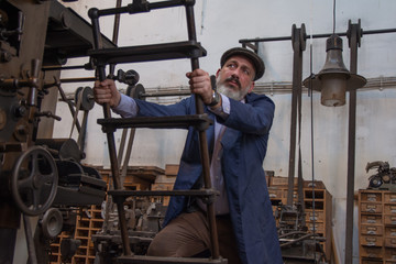 Fototapeta na wymiar Retro picture of a man working on old printing press