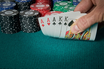 view of a game table with green carpet where are the cards with full of aces and kings and the poker chips.