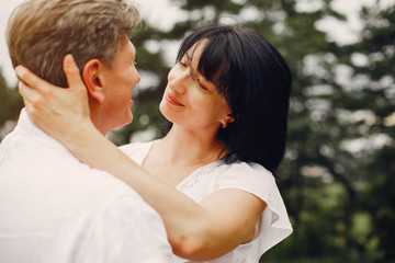 Adult couple in a summer field. Handsome senior in a white shirt. Woman in a white blouse