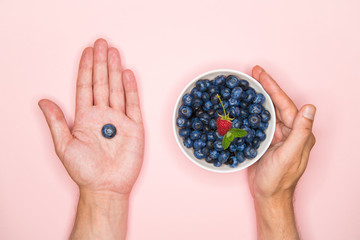 Blueberries in the hands. A man holds blueberries in his hands. Blueberries in a white bowl. Vitamins of nature. Berry nutrition. Place for writing. View from above