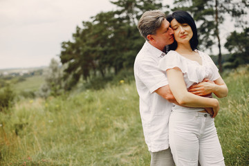 Obraz premium Adult couple in a summer field. Handsome senior in a white shirt. Woman in a white blouse