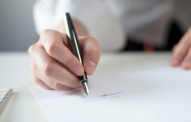 hand with pen signing a document