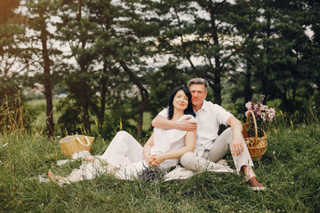 Adult couple in a summer field. Handsome senior in a white shirt. Woman in a white blouse