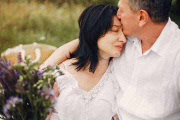 Fototapeta premium Adult couple in a summer field. Handsome senior in a white shirt. Woman in a white blouse