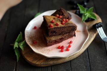 chocolate cake with prunes and cranberries on a dark wooden background.