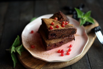 chocolate cake with prunes and cranberries on a dark wooden background.