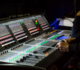 Sound engineer controls the settings on the mixing console panel  in sound recording studio for music, sound recording, concert activities